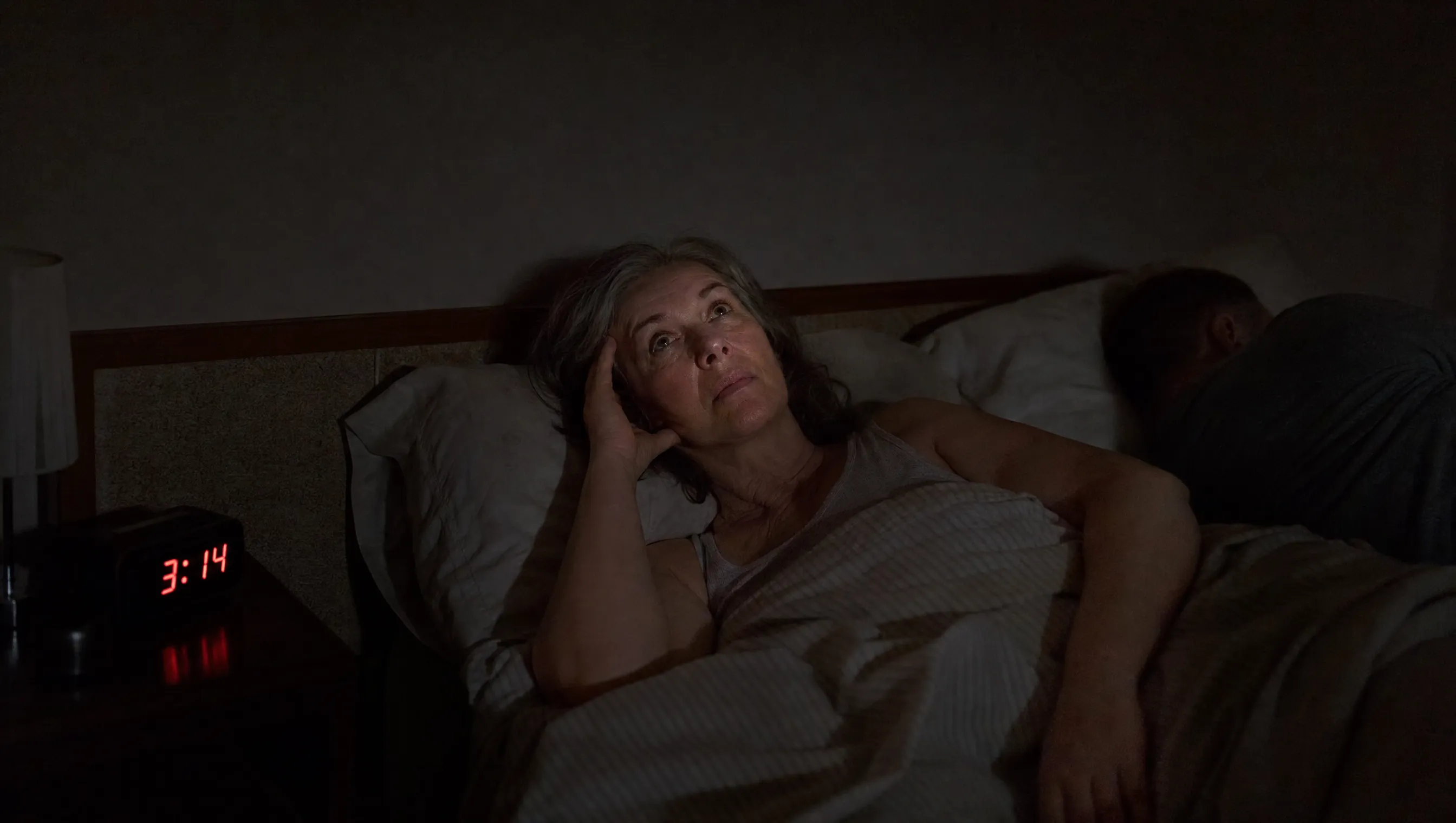 62-year-old woman lying awake at 3:14am, partner asleep beside her